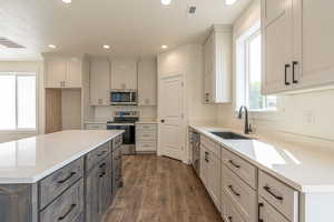 Kitchen with stainless steel appliances, a center island, light stone countertops, sink, and dark hardwood / wood-style floors