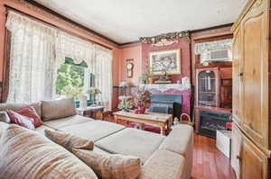 Living room with dark wood-type flooring, a wall unit AC, ornamental molding, and a textured ceiling