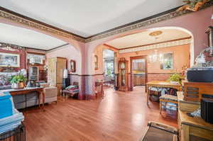 Living room with crown molding, an inviting chandelier, and hardwood / wood-style floors