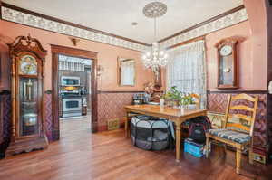 Dining room featuring a notable chandelier, hardwood / wood-style floors, a textured ceiling, and crown molding