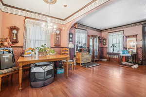 Dining area featuring a notable chandelier, crown molding, and hardwood / wood-style flooring