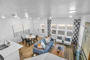 Living room featuring light hardwood / wood-style floors, sink, and a textured ceiling