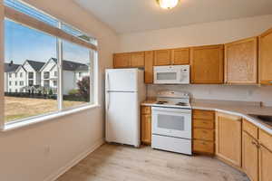 Kitchen with sink, white appliances, and light wood-type flooring