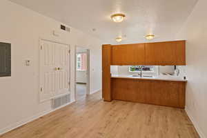 Kitchen with a healthy amount of sunlight, sink, light hardwood / wood-style flooring, and kitchen peninsula