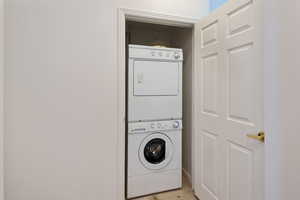 Washroom featuring light wood-type flooring and stacked washer / drying machine