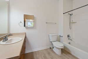 Full bathroom with washtub / shower combination, hardwood / wood-style floors, toilet, and large vanity