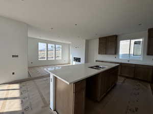 Kitchen with sink, a wealth of natural light, light stone counters, and a kitchen island with sink