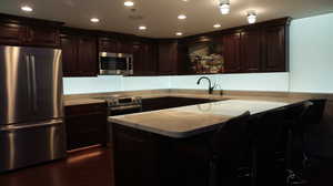 Kitchen with sink, dark wood-type flooring, dark brown cabinets, and stainless steel appliances