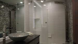 Bathroom featuring tiled shower and vanity