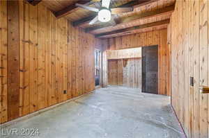 Spare room featuring wooden ceiling, wooden walls, and ceiling fan