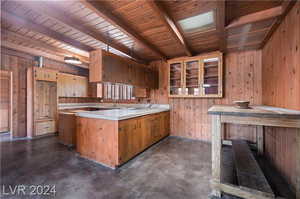 Kitchen with wood walls, sink, wood ceiling, and kitchen peninsula