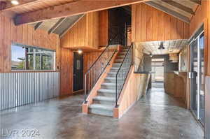 Interior space featuring beam ceiling, concrete flooring, and wood walls