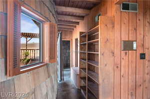 Hall with beam ceiling, wood walls, and wood ceiling