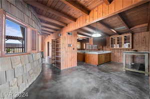 Kitchen featuring hanging light fixtures, beam ceiling, wood walls, and wood ceiling