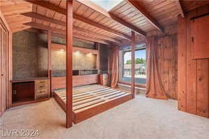 Unfurnished bedroom featuring carpet floors, lofted ceiling with skylight, and wood ceiling