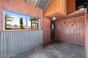 Empty room featuring wooden walls and vaulted ceiling