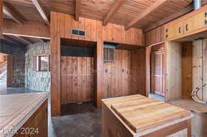 Kitchen featuring beamed ceiling, wood walls, wood ceiling, and tile counters