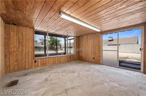 Spare room featuring concrete flooring, wood ceiling, and wood walls