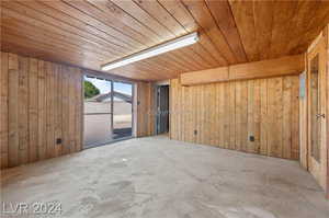 Empty room with wooden walls, concrete floors, and wood ceiling