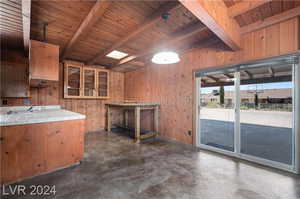 Kitchen with beam ceiling, decorative light fixtures, wood ceiling, wooden walls, and tile countertops