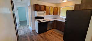 Kitchen featuring dark wood-type flooring, white appliances, sink, and decorative backsplash