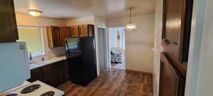 Kitchen with dark hardwood / wood-style floors, white appliances, hanging light fixtures, sink, and decorative backsplash