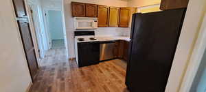 Kitchen with light hardwood / wood-style flooring, backsplash, and white appliances