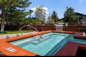 View of pool featuring a grill, a hot tub, and a wooden deck