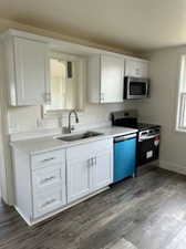 Kitchen featuring white cabinets, appliances with stainless steel finishes, sink, and hardwood / wood-style floors