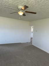 Spare room with ceiling fan and dark colored carpet