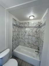 Bathroom featuring tiled shower / bath and toilet