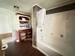 Bathroom featuring shower / bath combo, a textured ceiling, and wood-type flooring