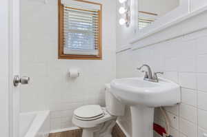 Bathroom featuring wood-type flooring, tile walls, and toilet