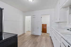 Kitchen featuring light hardwood / wood-style flooring, white cabinets, and tasteful backsplash