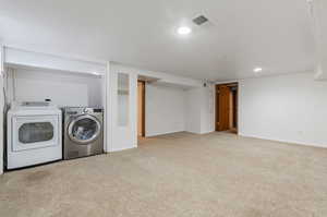 Laundry area featuring light carpet and washing machine and clothes dryer