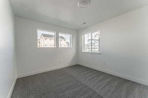 Unfurnished room featuring dark carpet and a textured ceiling