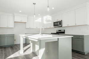 Kitchen with a kitchen island with sink, appliances with stainless steel finishes, and hardwood / wood-style flooring