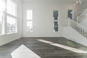 Unfurnished living room with a towering ceiling, dark hardwood / wood-style flooring, and an inviting chandelier