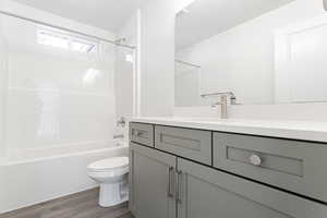 Full bathroom with vanity, toilet, shower / bath combination, and wood-type flooring