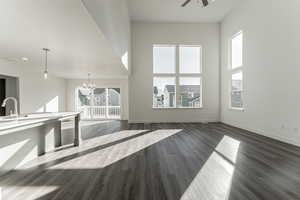 Unfurnished living room with sink, dark hardwood / wood-style floors, and ceiling fan with notable chandelier