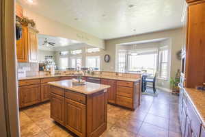 Kitchen with a kitchen island, kitchen peninsula, tasteful backsplash, ceiling fan, and appliances with stainless steel finishes