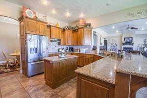 Kitchen featuring kitchen peninsula, stainless steel refrigerator with ice dispenser, sink, tasteful backsplash, and ceiling fan