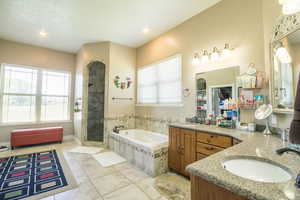 Bathroom featuring tile flooring, shower with separate bathtub, and vanity