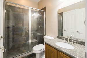 Bathroom featuring vanity, toilet, tile floors, and a shower with door