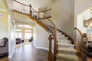 Stairs featuring a high ceiling, ceiling fan, and tile flooring