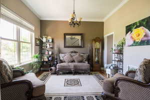 Living room with a notable chandelier, crown molding, and hardwood / wood-style flooring