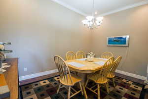 Dining room with an inviting chandelier, dark hardwood / wood-style flooring, and ornamental molding