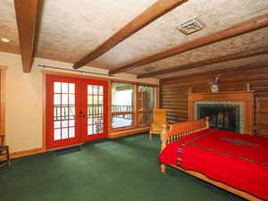 Primary suite with exposed wooden beam, log accents, and access to second story porch