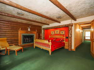 Primary suite on second floor with built-in bed alcove, log and beam accents, and private fireplace