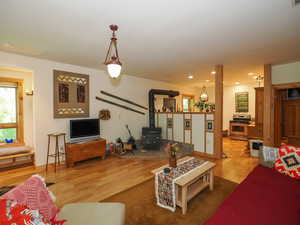 Basement living room with wood heating, featuring glass pieces in kitchen/living room wall with lights